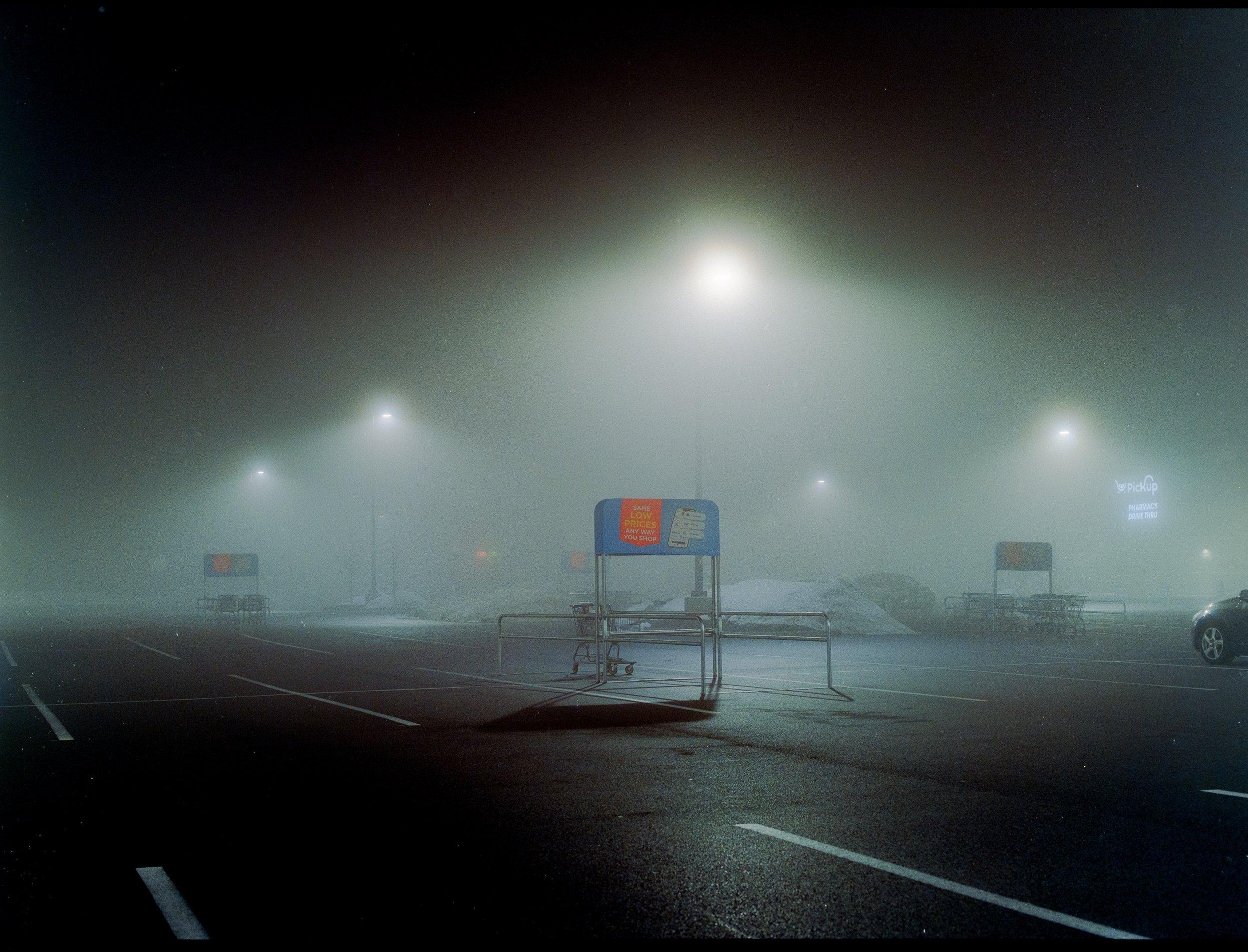 Streetlights glowing through night fog above an empty road